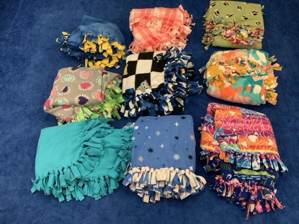 Nine folded tie blankets of various colors, arranged in squares